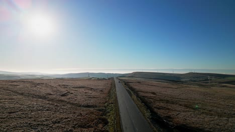 autos, die eine yorkshire-landstraße hinunterfahren, während die sonne tief am himmel steht und lens flare zeigt