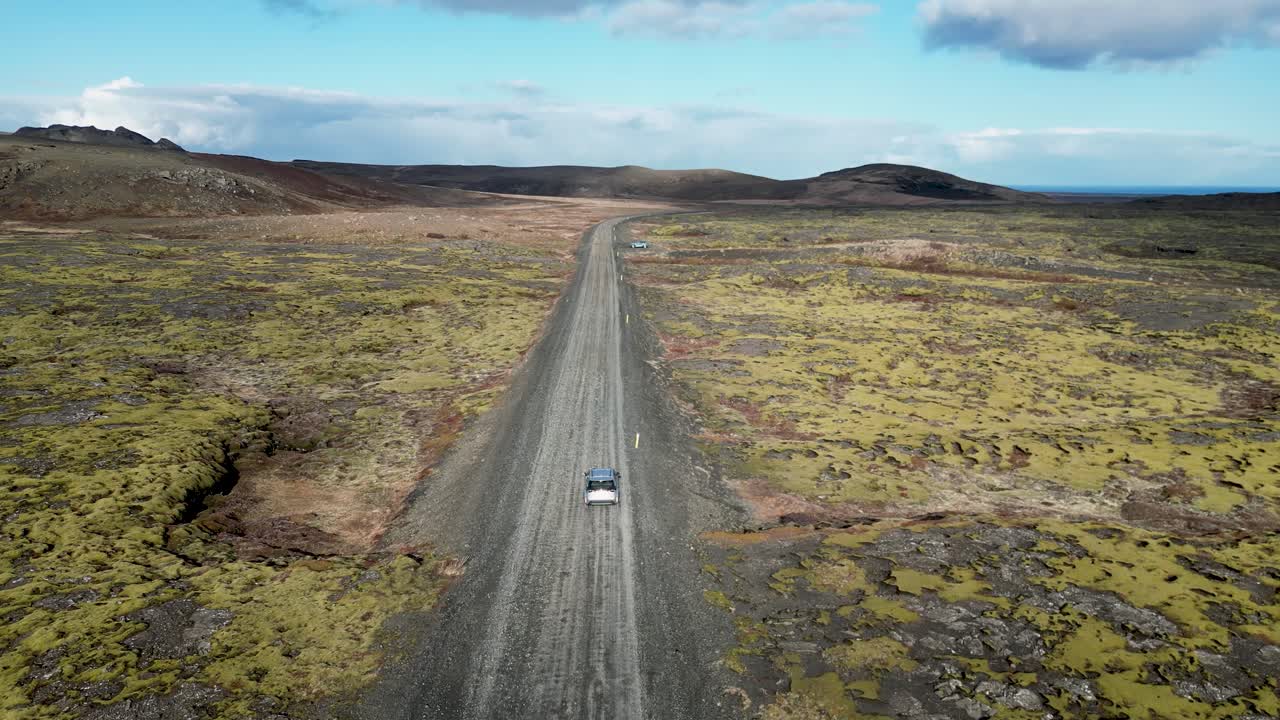 드론을 통해 아이슬란드의 풍경을 목격하고, 울불한 화산 지형을 가로질러 휘어지는 도로에서  차를 보십시오.