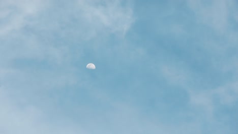 4k time lapse of bright moon is rising in evening of summer time with sunlight and clouds seeing fast moving of planet. it shows beautiful clear blue sky with space of sky movement.