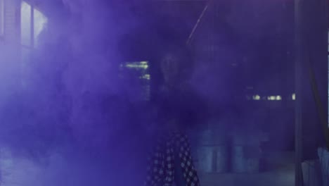 mixed race woman holding blue flare standing in an empty building
