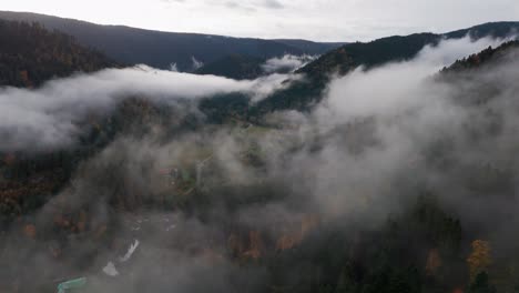 aerial view flying above thick clouds over mystical automnal mountain forest, 4k