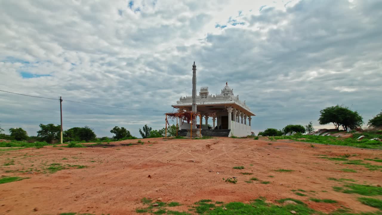 newly constructed Hindu temple with dwajasthambam and rainy clouds at day time, low angle, push in, drone shot, 4k.