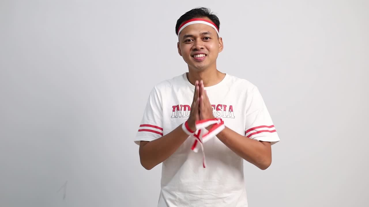 Young Indonesian man making Namaste greeting gesture with Indonesia Independence day concept