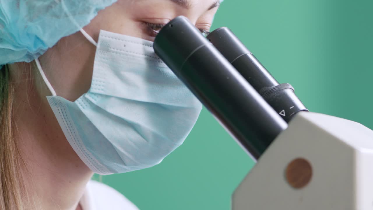 실험실 에서 현미경 을 사용하는 과학자