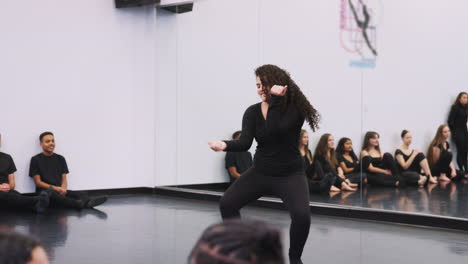 female dance student at performing arts school performs street dance for class and teacher in studio