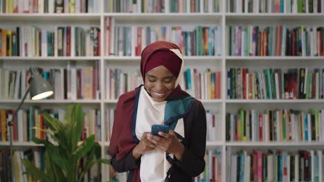 Retrato-De-Una-Joven-Y-Encantadora-Mujer-Afroamericana-Riéndose-Mirando-A-La-Cámara-Estudiante-Parada-En-La-Biblioteca