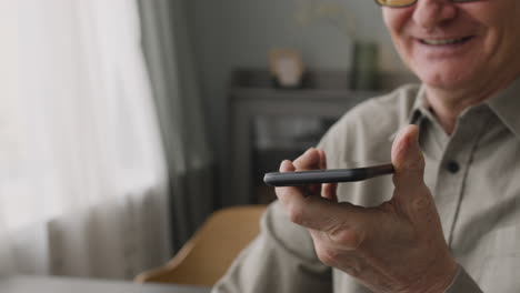 älterer-Mann,-Der-Zu-Hause-Freihändig-Telefoniert,-Während-Er-Zu-Hause-Auf-Dem-Sofa-Im-Wohnzimmer-Sitzt