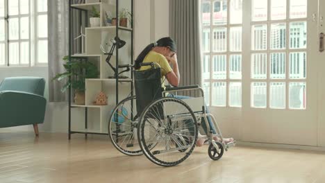 disappointed asian kid girl  sitting in a wheelchair near door in the house