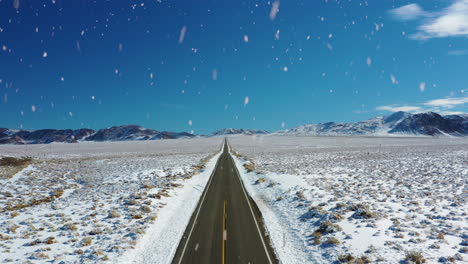 iconic american country road in winter season during snowfall, aerial fly forward view