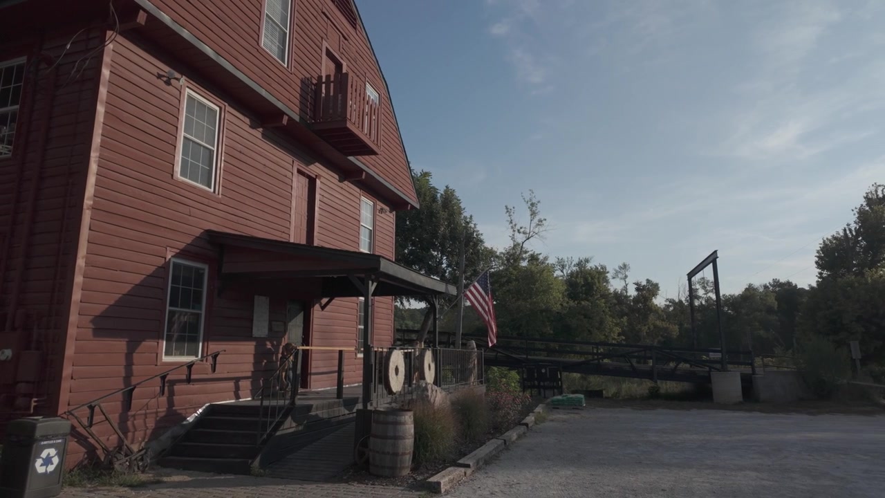 Pan right shot of flag at entrance of War Eagle Mill