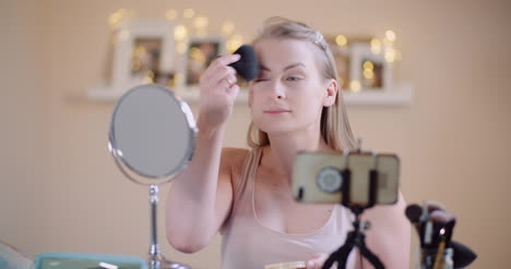 young woman doing makeup in front of mirror at home 2