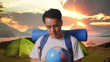 man with backpack and globe on a camping trip at sunrise