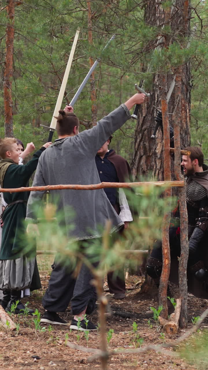 valientes guerreros levantan espadas en el entrenamiento en madera de abeto a cámara lenta. eventos históricos club de reconstrucción. batalla con viejas armaduras para divertirse