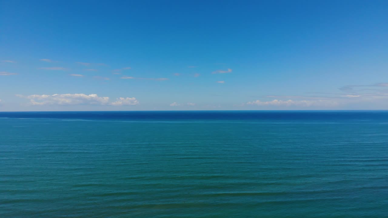 여름날 밝은 하늘과 흰 구름에 닿는 청록색 바다 수평선