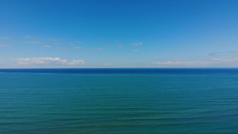 sea horizon of turquoise blue water touching bright sky and white clouds on a summer day