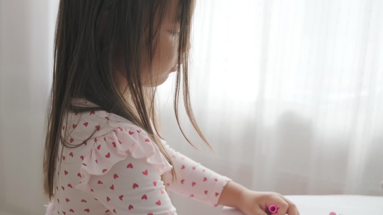 joven sentada en una mesa, dibujando con lápices de colores. ideal para temas de creatividad, desarrollo infantil, aprendizaje y actividades artísticas en un ambiente interior acogedor.