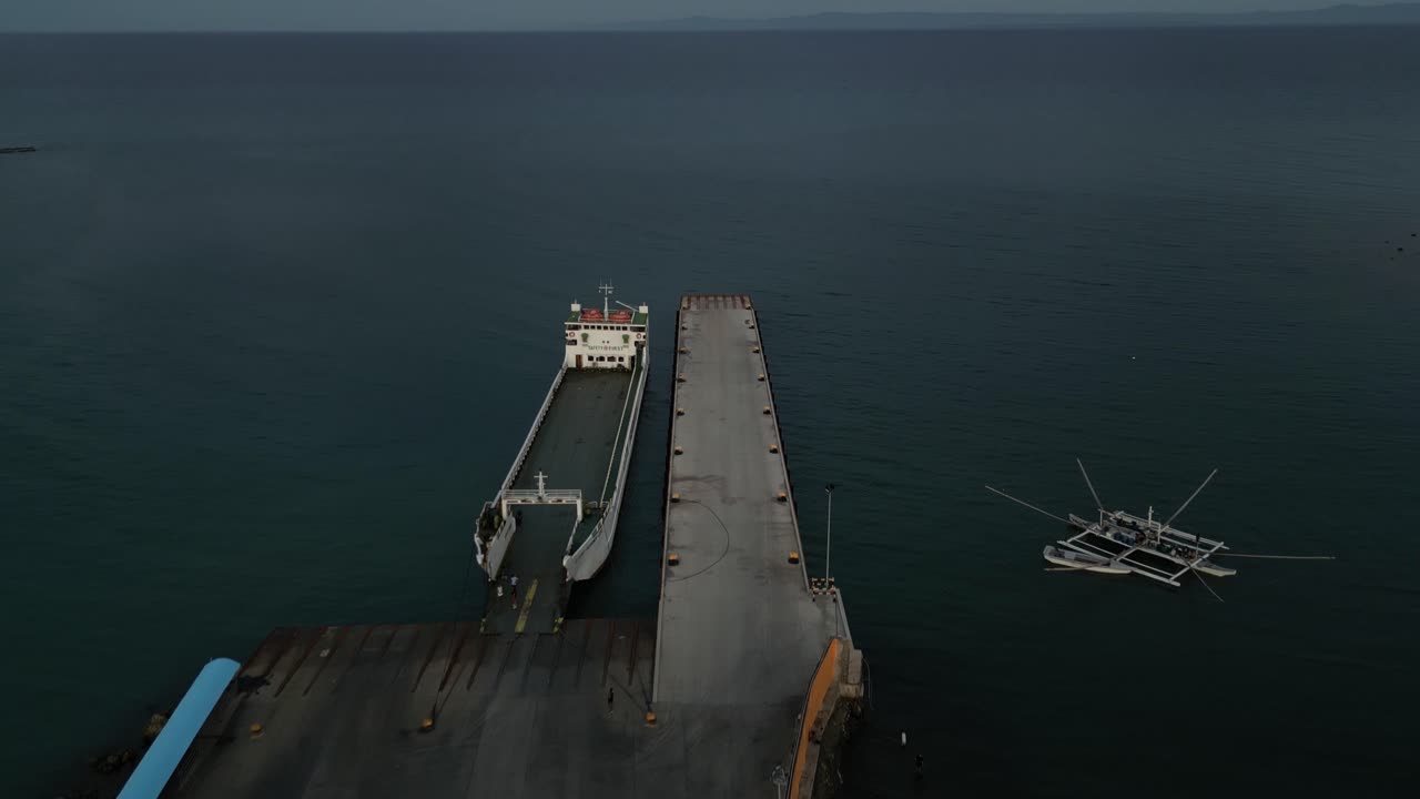 panorámica aérea de la costa del puerto de taloot argao al amanecer, capturando barcos y transbordadores en el muelle y el océano circundante en cebu, filipinas