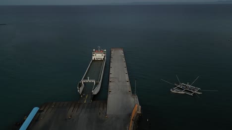 sweeping aerial pan of taloot argao port's coastline at sunrise, capturing boats and ferry at dock and the surrounding ocean in cebu, philippines