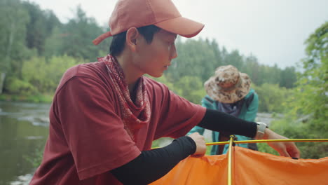 female tourists setting up campsite by river