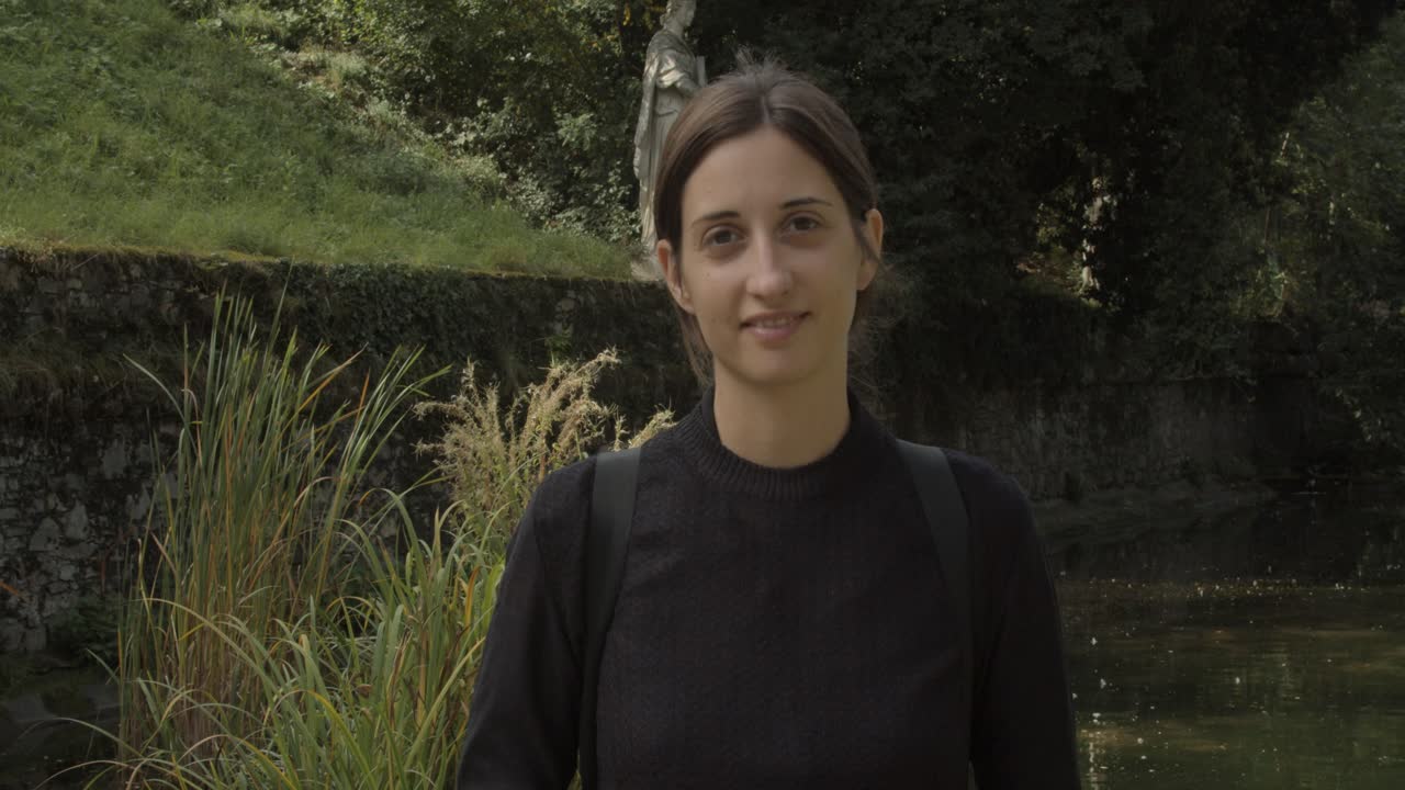 niña sonriendo frente a la estatua antigua a lo largo de la piscina en stadt park en graz, austria, de cerca