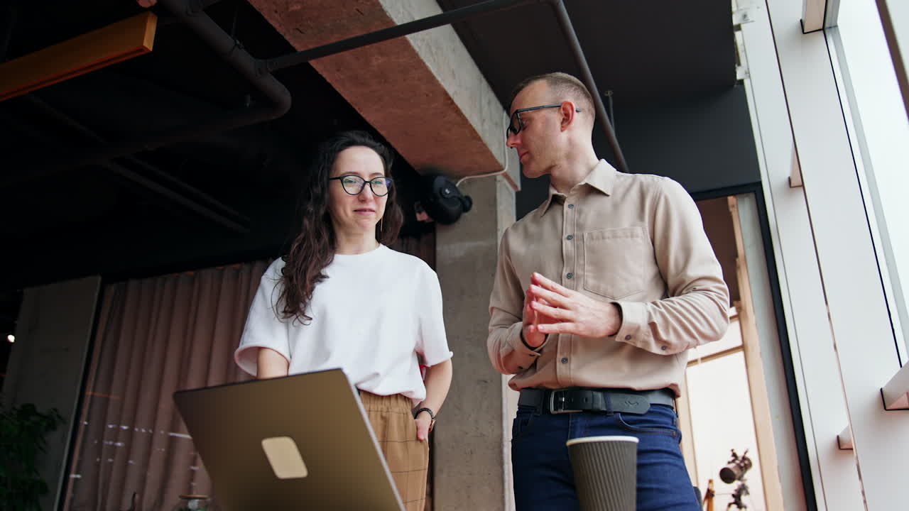 Teammates discussing issues on computer screen. Woman speaks and man is carefully listening to colleague.