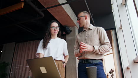 teammates discussing issues on computer screen. woman speaks and man is carefully listening to colleague.