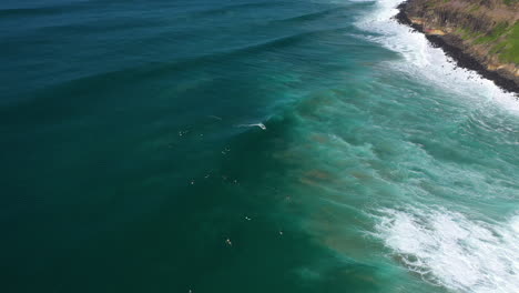 4k aerial shot of people surfing by lennox head, australia