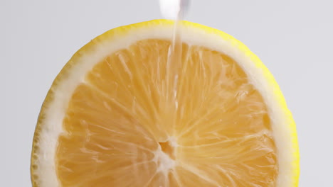 Slow-Motion-Macro-Shot-of-Flowing-Water-from-Lemon-Slice-on-white-Background