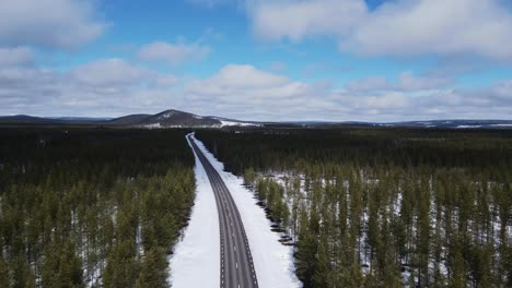 scenic aerial view of empty highway in snowy sweden surrounded by lush coniferous foliage