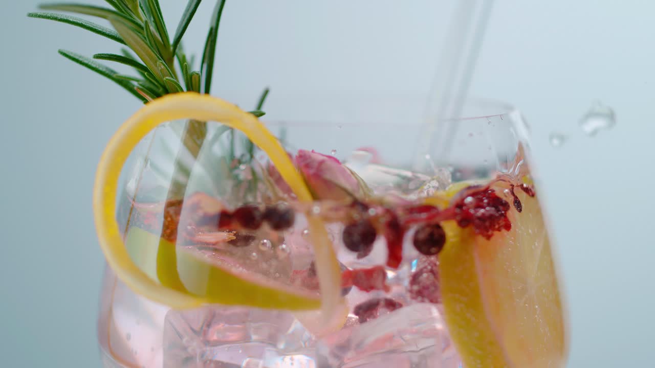 Cubetto di ghiaccio che cade in un bicchiere d'acqua aromatizzata alla frutta