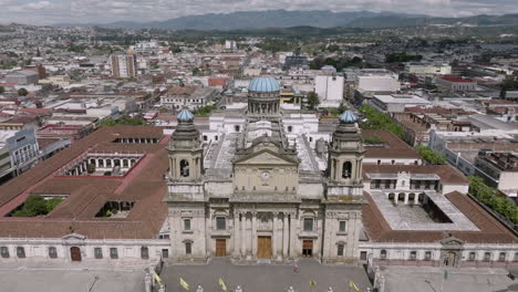 Slow-aerial-flyover-of-the-Metropolitan-Cathedral-of-Santiago-of-Guatemala-in-Guatemala-City,-Guatemala-with-traffic-in-the-foreground