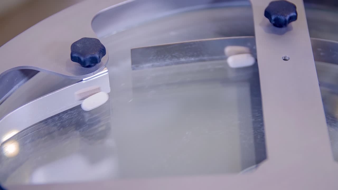 Extreme closeup of white pills for COVID-19 treatment spinning during its mass production