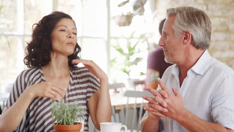 mujer de mediana edad gesticulando mientras habla con su viejo amigo blanco en una mesa en un café, de cerca