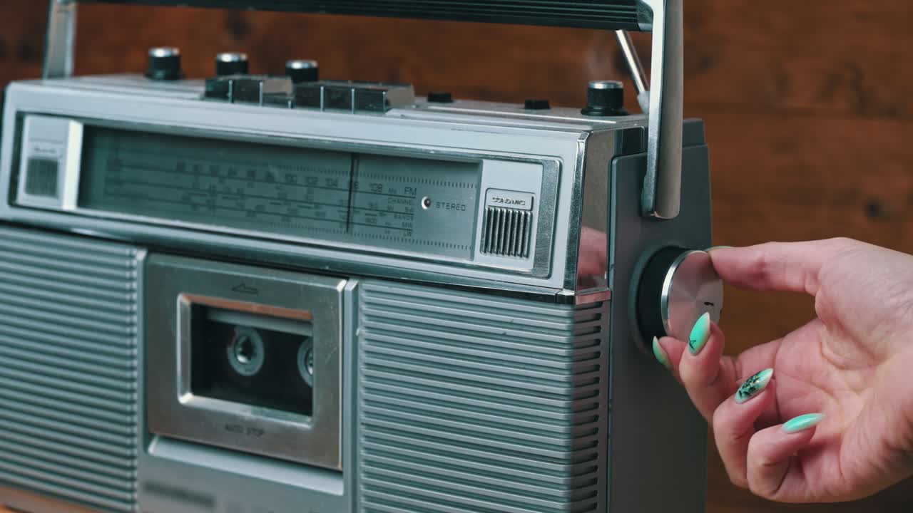 소녀의 손은 레트로 라디오 테이프 레코더의 버튼을 회전시키고 누릅니다.