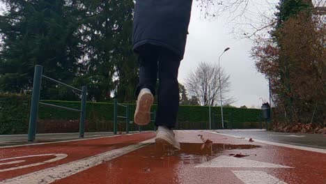 unrecognizable carefree child girl holding doll jumps into puddle on bicycle lane after rain