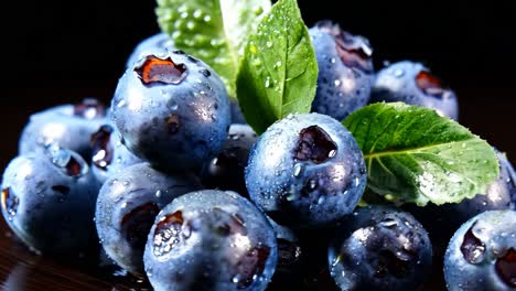 fresh blueberries with droplets and mint leaves on a dark background