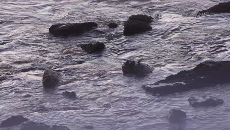 seascape with some fog, waves of salt water hitting the rocks at estoril beach, reflections of waves on the surface of the water, portugal