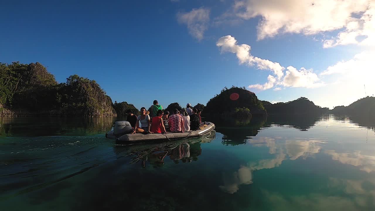 a rubber inflated boat is cruising through a calm lagoon in the morning peacefully