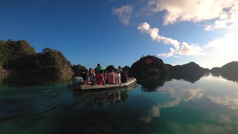 a rubber inflated boat is cruising through a calm lagoon in the morning peacefully