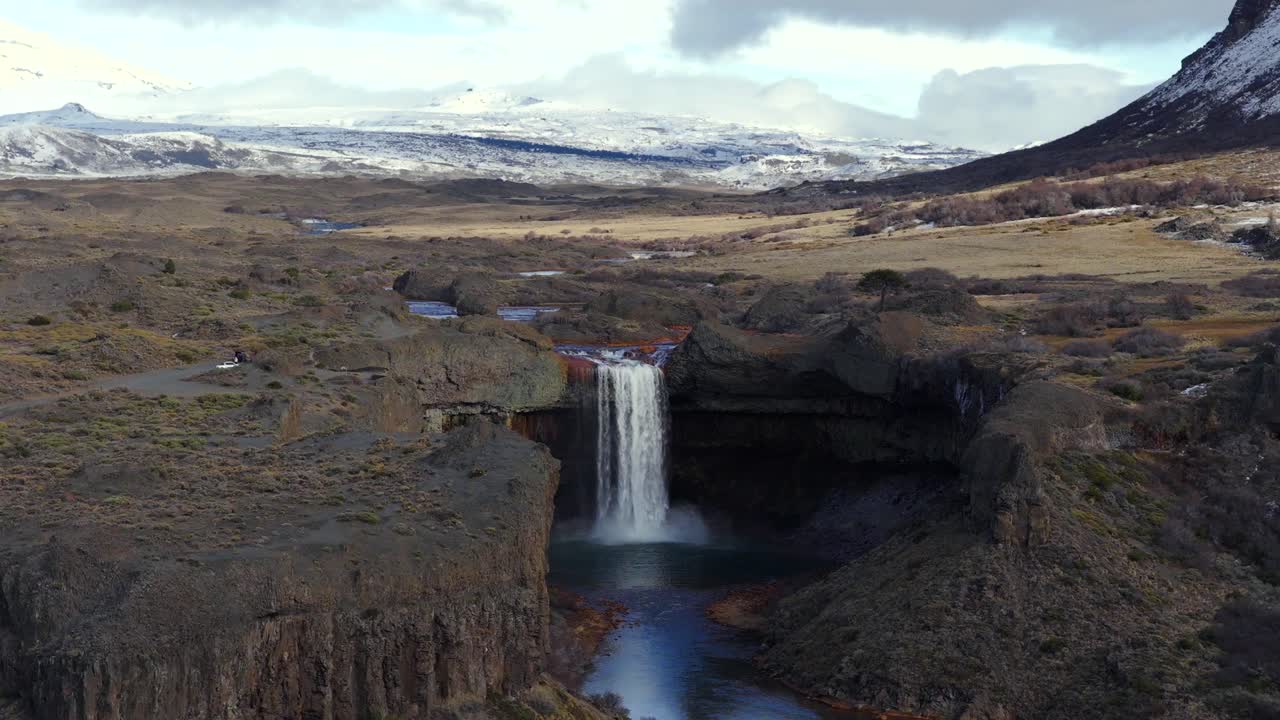 Drone view of Salto del Agrio waterfall surrounded by rocky cliffs and snowy Andes mountains, Caviahue, Argentina