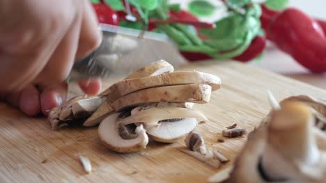 person chopping mushrooms on cutting board