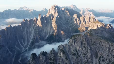 luftaufnahme von sonnenlicht, das morgens eine bergkette in dolomiten badet - dichte wolken, die das tal bedecken