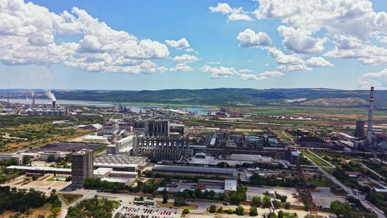 Vista di una vasta area industriale con fabbriche e macchinari vicino a un fiume sotto un cielo nuvoloso durante il giorno