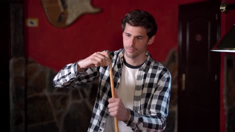 focused man chalking pool cue before game