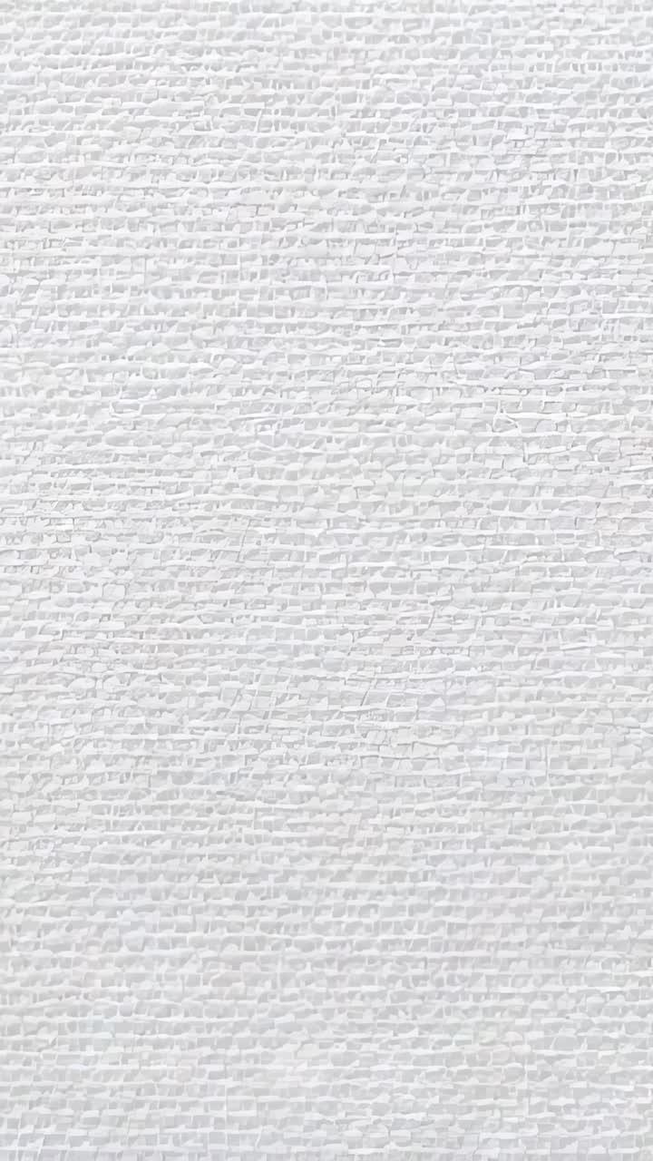 Vertical video: Moving camera showing white canvas in studio for detail, revealing threads, knots