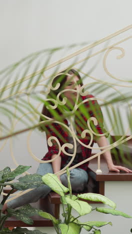 young woman rests on apartment staircase. relaxed female home owner poses for camera sitting on stairs with forged handrails. luxury residence