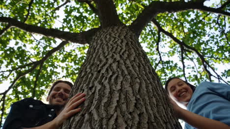 hands reaching for or embracing a tree trunk from a low angle