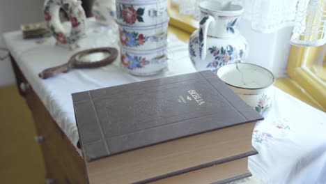 old hungarian bible on table with vintage bowl, pitcher, mirror in old house