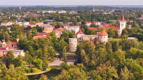 drone footage showcasing cesis old town, medieval castle, and lush green landscape.