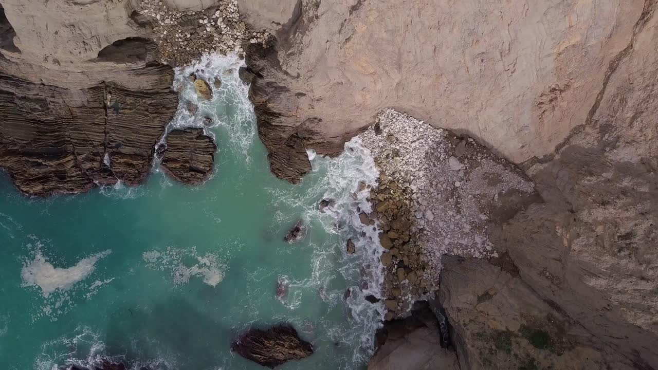 Volando su e via da una spiaggia rocciosa di ciottoli con onde sulla costa della California vicino alla Highway One